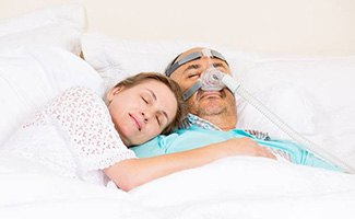 Woman and man with CPAP mask sleeping soundly