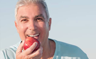 Smiling senior man eating an apple