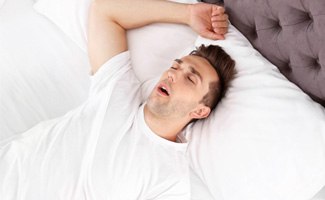 Man with sleep apnea in Reno, NV lying in bed while snoring