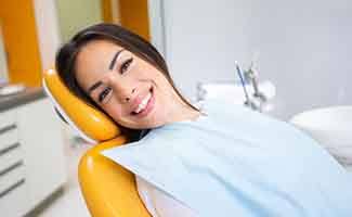 Female dental patient sitting in dental chair smiling