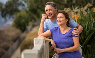 Older couple with dental bridges in Reno smiling outside