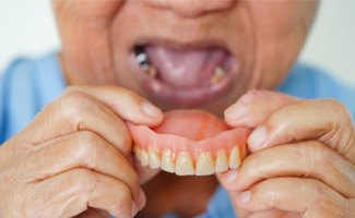 A woman removing a denture from her mouth