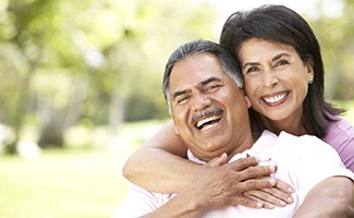 Older couple with dental implants in Reno smiling outside