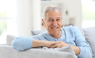 Senior man with implant dentures in Reno, NV relaxing on couch