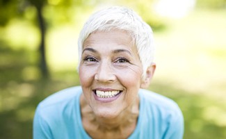 Senior woman outside smiling with implant dentures in Reno, NV