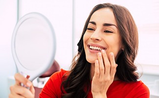 a patient checking her smile after getting dental implants