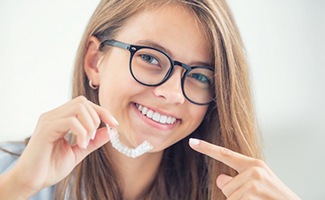 Woman smiling and pointing to Invisalign in Reno