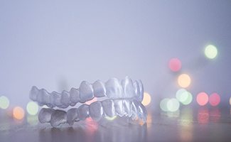 Smiling woman holding Invisalign in Reno in front of her