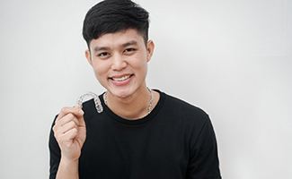 Smiling young man holding Invisalign in Reno