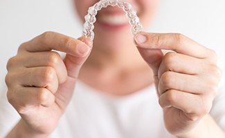 Smiling woman holding Invisalign in Reno in front of her