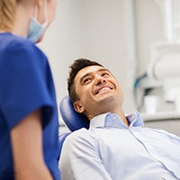 Male patient smiling at dental assistant while sitting in treatment chair