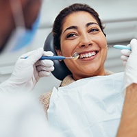 Woman smiling while looking at dentist during exam