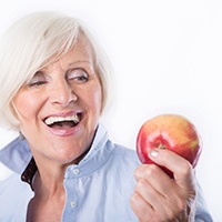 older woman about to eat an apple as part of a healthy diet