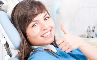 A young woman giving the thumbs up in the dentist chair