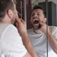 Reno patient checking gums in bathroom mirror