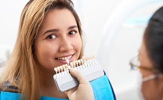 cosmetic dentist in Reno holding a row of veneers to a patient’s smile 