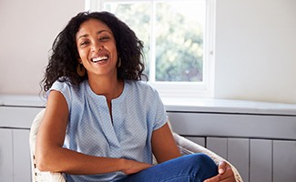 Woman in blue shirt smiling while sitting on chair at home