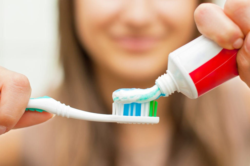 woman smiling while brushing her teeth
