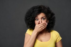 Concerned woman covering her porcelain veneers in Reno with her hands