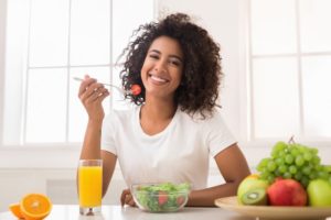 woman eating salad to maintain a healthy smile