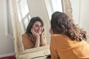 Woman looking in mirror after fixing small teeth