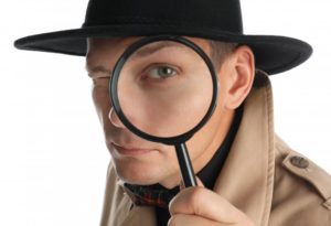 male detective looking through magnifying glass