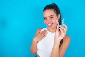 a person smiling and holding an Invisalign tray