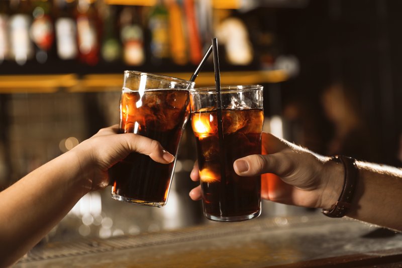 Two people clinking glasses of soda together