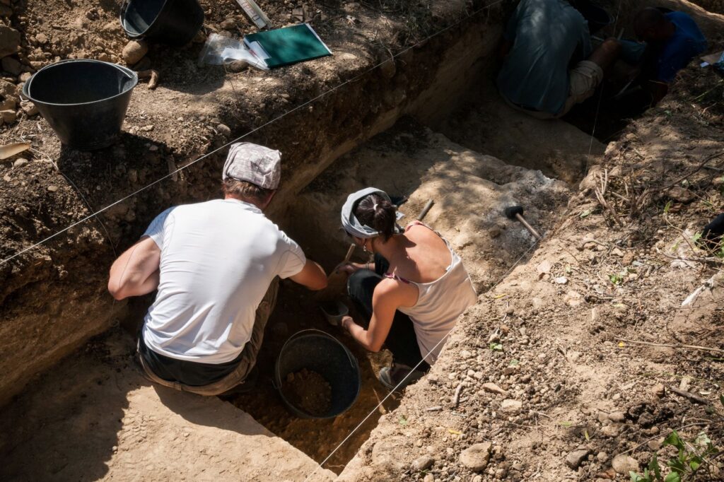 Man and woman in earthy pit with digging tools