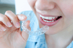 a patient smiling and holding their Invisalign tray