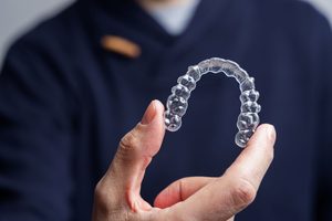 Someone in navy blue scrubs holding Invisalign tray