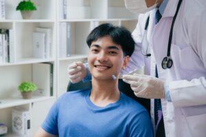 Young man with blue shirt in dental chair about to undergo exam